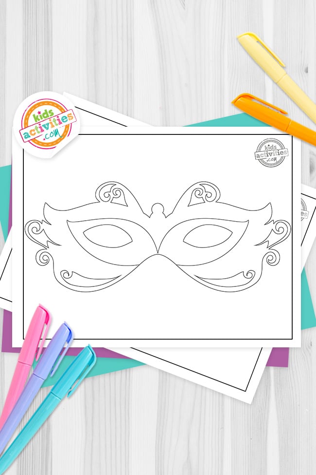 Black and white printed masquerade mask template coloring pages, made with simple lines for kids on top of blue-green and purple sheets with assorted markers on a dark grey background. printed pdf version from Kids activities blog.